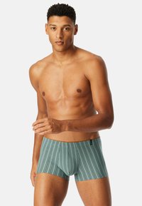 Men's boxer briefs in a teal color with vertical stripes. Stretch fabric with a soft texture and contrasting waistband. Mid-thigh length.