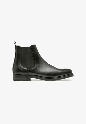 Bottine Chelsea en cuir noir avec une texture lisse, des panneaux latéraux élastiques, une languette et un talon bas empilé. Convient à diverses occasions.