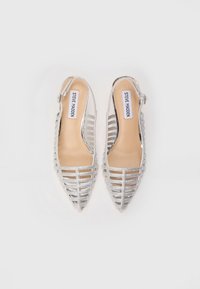 Sølv slingback hæler med spiss tå, laget av mesh og metalliske detaljer. Har et horisontalt stripet design og åpne sider.