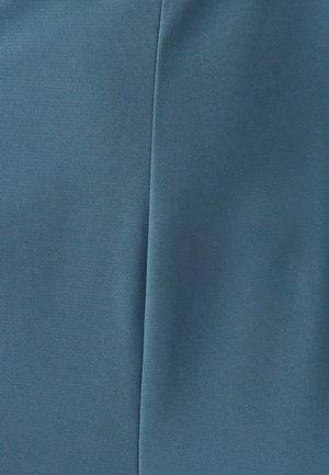 Turquoise stof met een gladde textuur, voorzien van een lichte glans. De stof is gevouwen en toont een naad en een doorlopend oppervlak zonder patronen.