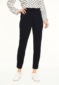 Navy Jogginghose aus weichem Material, mit einem Kordelzugbund, Reißverschluss-Taschen und schrägen Nähten für einen maßgeschneiderten Sitz.
