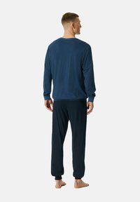 Laivastonsiniset pyjamat, joissa on kuvioitu pitkähihainen paita, jossa on ribbikantit, sekä pehmeät, joustavat vyötäröhousut, joissa on sama kuosi. Ei näkyviä metalliosia.