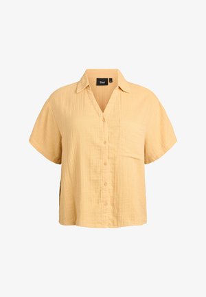 Īsām piedurknēm, ar pogām aiztaisāma vaļīga krekls gaiši dzeltenā krāsā ar apkakli un krūšu kabatu, izgatavots no viegla, teksturēta auduma.