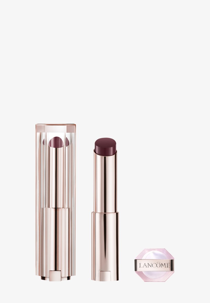 Lipstick in a clear faceted case, rose gold accents. Dark plum shade in a smooth bullet. Small pink hexagonal base with "Lancôme" label.