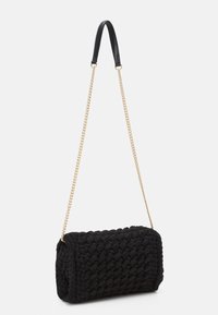 Borsa a tracolla nera di forma cilindrica, con un corpo in tessuto testurizzato, una tracolla in pelle e una catena dorata per il trasporto.