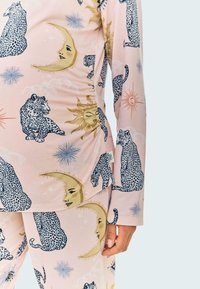 Rosa pyjamaset med leopardmönster, sol- och månadekor. Har lång ärm och en figurnära design, tillverkad av mjukt, stretchigt tyg.