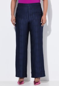 Kalhoty širokého střihu s námořnickým vzorem vyrobené z texturované látky, s vertikálními pruhy. Spárované s růžovými metalickými lodičkami s špičatou špičkou.