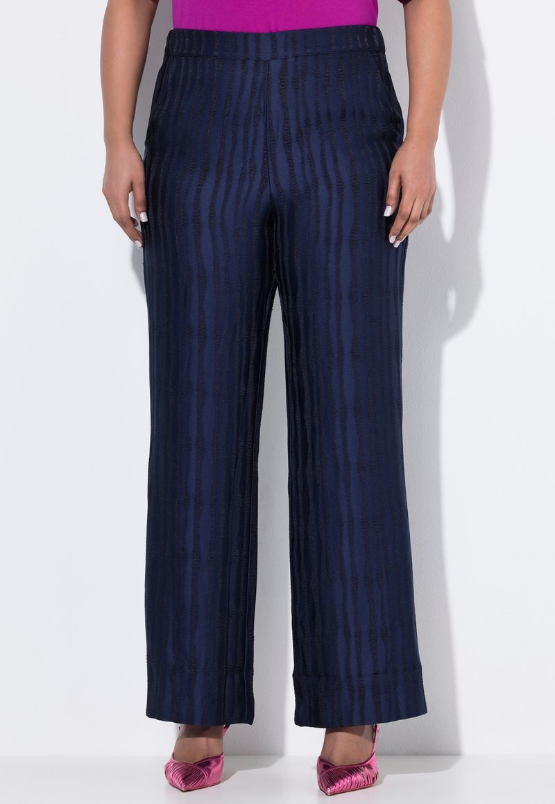 Kalhoty širokého střihu s námořnickým vzorem vyrobené z texturované látky, s vertikálními pruhy. Spárované s růžovými metalickými lodičkami s špičatou špičkou.