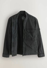 Fekete könnyű dzseki állógallérral, elöl cipzárral, mellkasnál fedeles zsebbel és hosszú ujjakkal, fehér háttér előtt bemutatva.