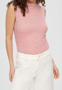 Randiga toppar i röd och vit utan ärmar, gjorda av ribbad tyg, kombinerat med högmidjade, ljusa jeans.