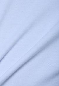 Zbliżenie gładkiego, jasnoniebieskiego materiału z subtelnym diagonalnym splotem i delikatnymi fałdami.