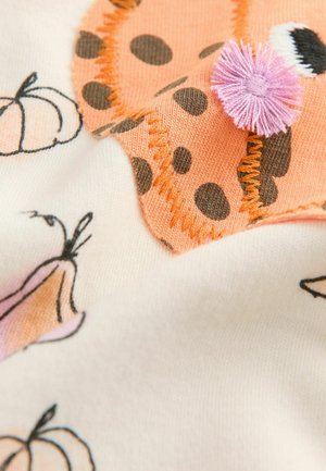 Tissu doux avec un motif tacheté orange et marron, agrémenté de pompons roses, associé à des citrouilles illustrées sur un fond crème.