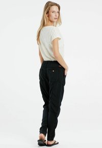 Zwarte, taps toelopende cargobroek met een elastische tailleband, zijzakken en subtiele stikdetails; gecombineerd met een lichte top met korte mouwen.