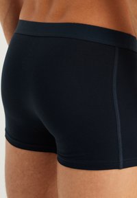 Temno modri bokserice iz gladkega blaga, z elastičnim pasom in ravnim šivom za udobje in prileganje.