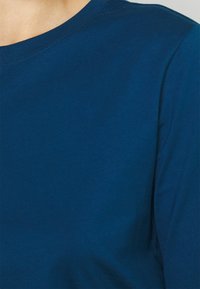 Navy blue long-sleeve t-shirt with a round neckline, made of smooth cotton fabric, featuring a simple and clean design.