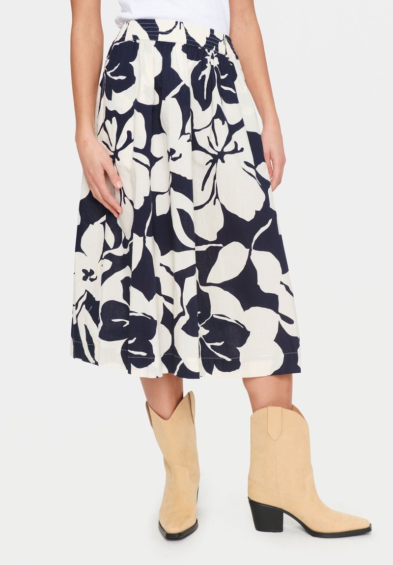 Midikjol med blommönster i marinblått och vitt, med elastisk midja, plisseringar och fickor, matchad med beige cowboyboots.