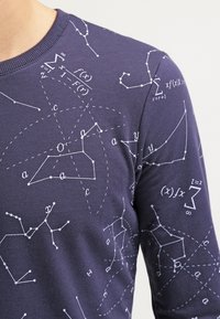 Felpa in cotone blu navy con simboli matematici bianchi, equazioni e forme geometriche disposte in un motivo sparso.