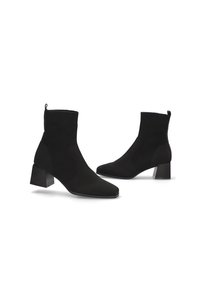 Botas de tobillo negras con parte superior de punto, punta cuadrada y acabado texturizado. El tacón bloque afilado mide aproximadamente 3 pulgadas.