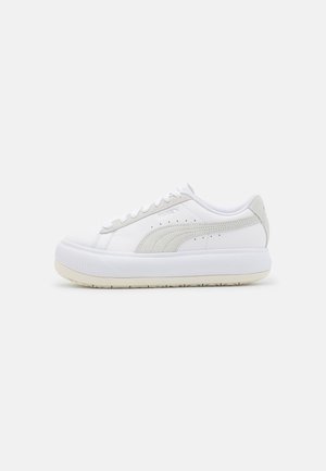 Białe niskie sneakersy z grubą podeszwą, perforowanym logo na boku, wiązane oraz jasnoszare zamszowe akcenty na pięcie i bokach.