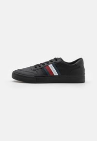 Sneaker nera con tomaia sintetica liscia, caratterizzata da strisce orizzontali rosse e blu, suola in gomma testurizzata e design con lacci.