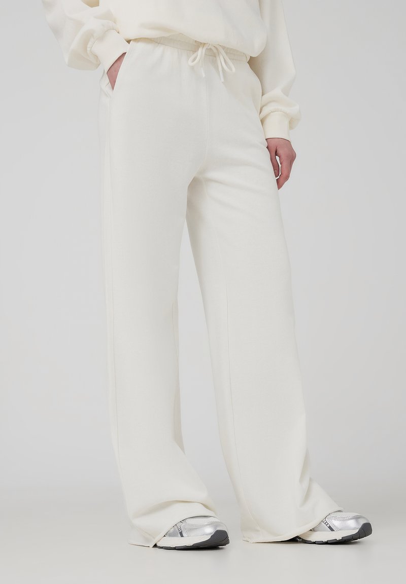 Pantaloni della tuta bianchi e larghi con vita elastica e cordoncino. La morbida texture del tessuto e i dettagli di design puliti enfatizzano il comfort.