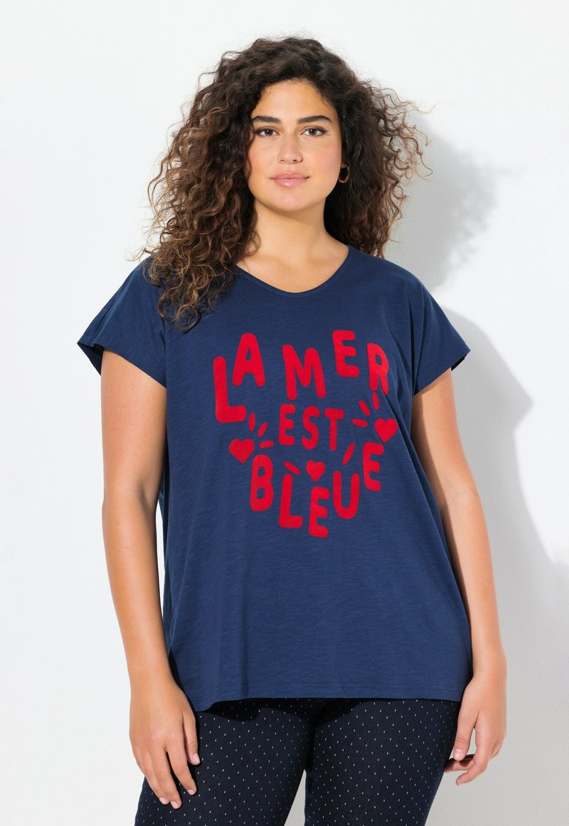 Tmavě modré tričko s krátkým rukávem a červeným nápisem "LA MER EST BLEUE." Měkká látka, volný střih, kulatý výstřih, v kombinaci s legínami s puntíky.