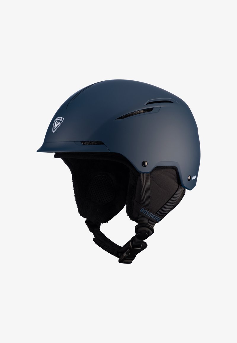 Tummansininen hiihtokypärä, jossa on matta pinta. Varustettu tuuletusaukoilla, pehmeillä korvatyynyillä ja säädettävällä leukahihnalla. Logo etupinnassa.