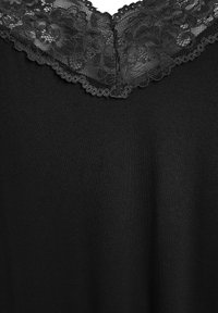 Top nero con design a V, adornato con un bordo in pizzo floreale lungo il collo. Il tessuto è liscio e leggermente strutturato.