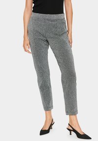 Szare metaliczne spodnie o dopasowanym kroju, z elastycznym pasem i zwężanymi nogawkami. Noszone z czarnymi szpilkami typu slingback dla kontrastu.