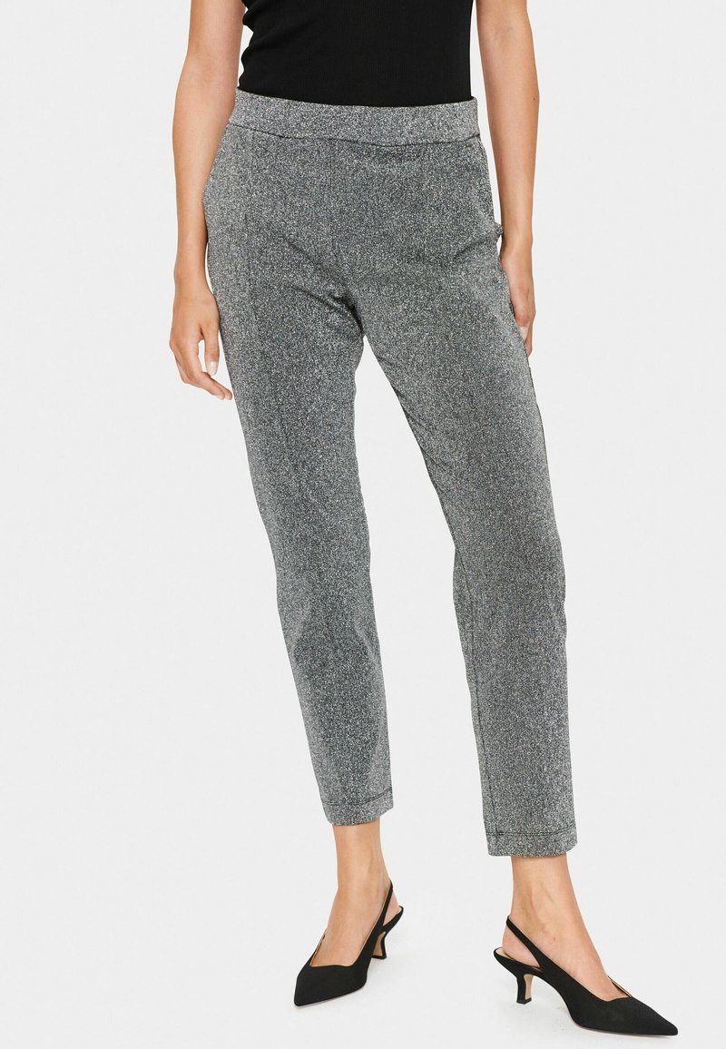 Szare metaliczne spodnie o dopasowanym kroju, z elastycznym pasem i zwężanymi nogawkami. Noszone z czarnymi szpilkami typu slingback dla kontrastu.