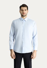 Lichtblauw overhemd met lange mouwen, gemaakt van gladde stof met een spread collar, voorzien van een knoopsluiting aan de voorkant en een getailleerde pasvorm.