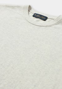 Světle šedá bavlněná mikina s kulatým výstřihem, která má jemnou strukturu a malou námořnickou etiketou uvnitř výstřihu.