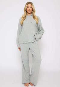Conjunto de dos piezas en gris claro, con textura suave, que incluye una parte superior de manga larga con capucha y pantalones de pierna ancha, diseñado para comodidad y un ajuste relajado.