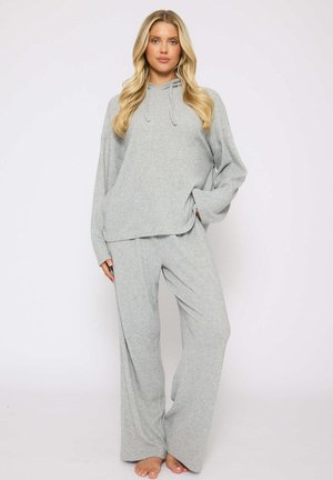 Ensemble en deux pièces de couleur gris clair, à la texture douce, comprenant un haut à capuche à manches longues et un pantalon large, conçu pour le confort et une coupe décontractée.
