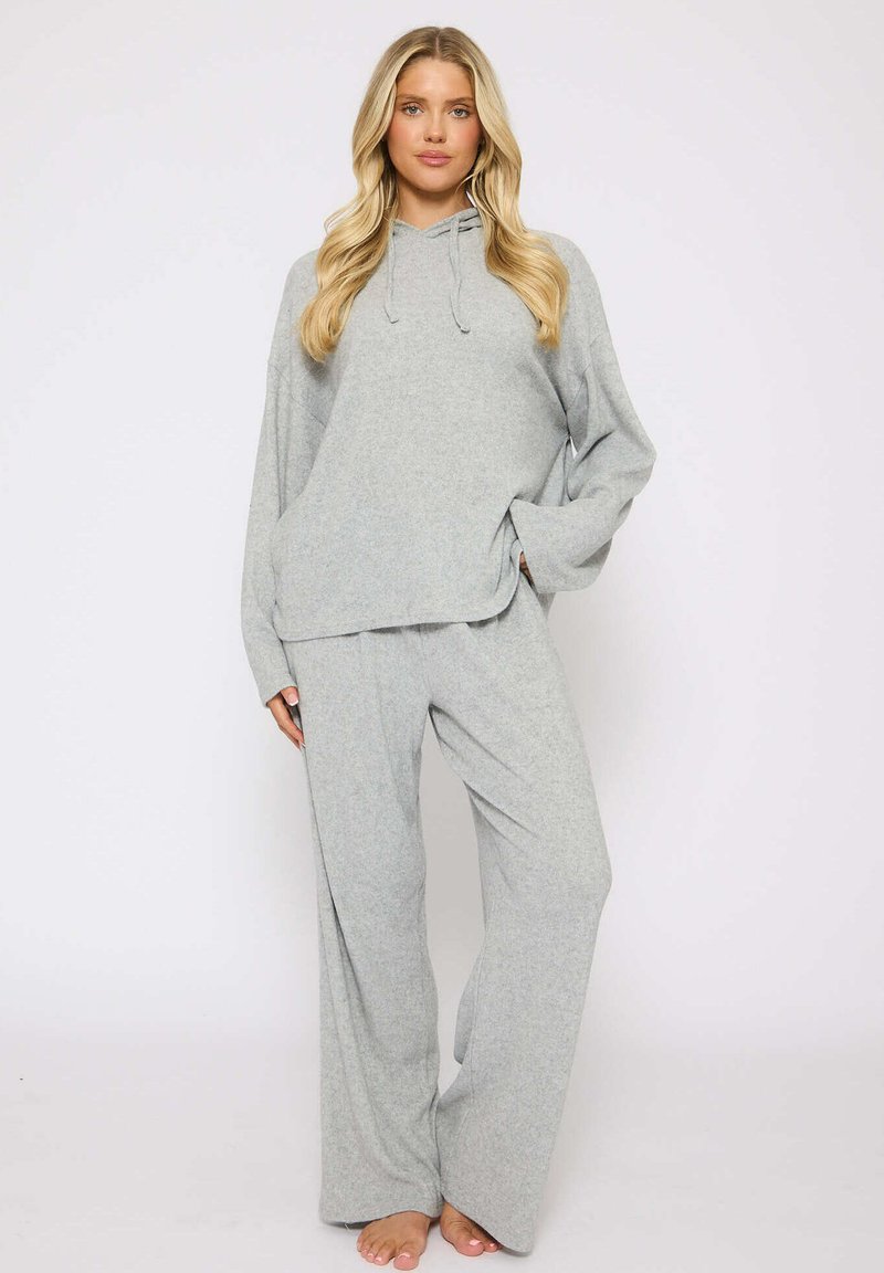 Conjunto de dos piezas en gris claro, con textura suave, que incluye una parte superior de manga larga con capucha y pantalones de pierna ancha, diseñado para comodidad y un ajuste relajado.