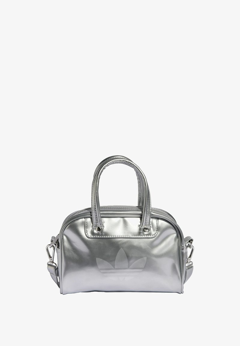 Siva metalik torbica s dva gornja ručka, zatvaranje na zip i urezani logo sprijeda. Glatka tekstura i kompaktan dizajn.