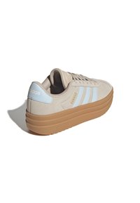 Beige Adidas sneaker with light blue stripes and heel tab, thick brown sole, and beige laces, shown at an angle on a white background.