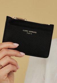 Black leather cardholder with a textured surface, featuring a gold logo and a zip closure. The design includes multiple card slots on one side.