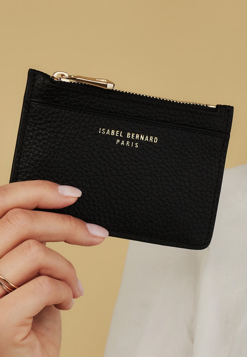 Black leather cardholder with a textured surface, featuring a gold logo and a zip closure. The design includes multiple card slots on one side.