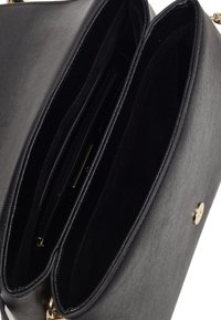 Borsa a mano in pelle nera con due scomparti, rivestimento interno morbido e chiusura circolare in oro. Presenta un'esterno testurizzato e una tasca con zip.