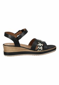 Sandales compensées noires avec des brides tressées blanches et noires, une semelle intérieure en cuir marron et une plateforme texturée semblable au bois avec une semelle extérieure en caoutchouc.
