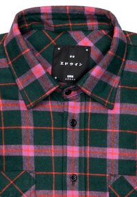 Green and red plaid shirt in flannel fabric. Features a button-down collar, black buttons, and a prominent brand label inside the collar.