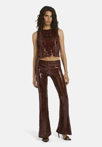 Een bronzen pailletten crop top gecombineerd met flared paillettenbroeken, met een slank ontwerp en glanzende textuur, wat zorgt voor een samenhangende outfit.