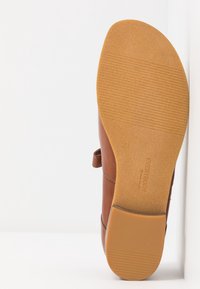 Hnědá kožená bota s hladkým svrškem, vybavená páskem. Podešev je gumová s texturovaným gripem. Velikost označena jako 37.