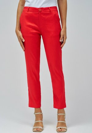Pantalons ajustés rouges avec une coupe slim, dotés d'un devant plat, d'un bouton à la taille et d'une coupe au niveau de la cheville. Tissu lisse et détails minimaux.