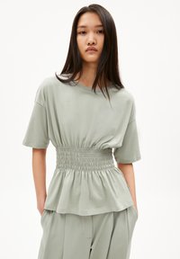 Hellgrünes Peplum-Top aus weichem Stoff, mit einem gerafften Bund und kurzen Ärmeln, lockerer Passform und rundem Ausschnitt.