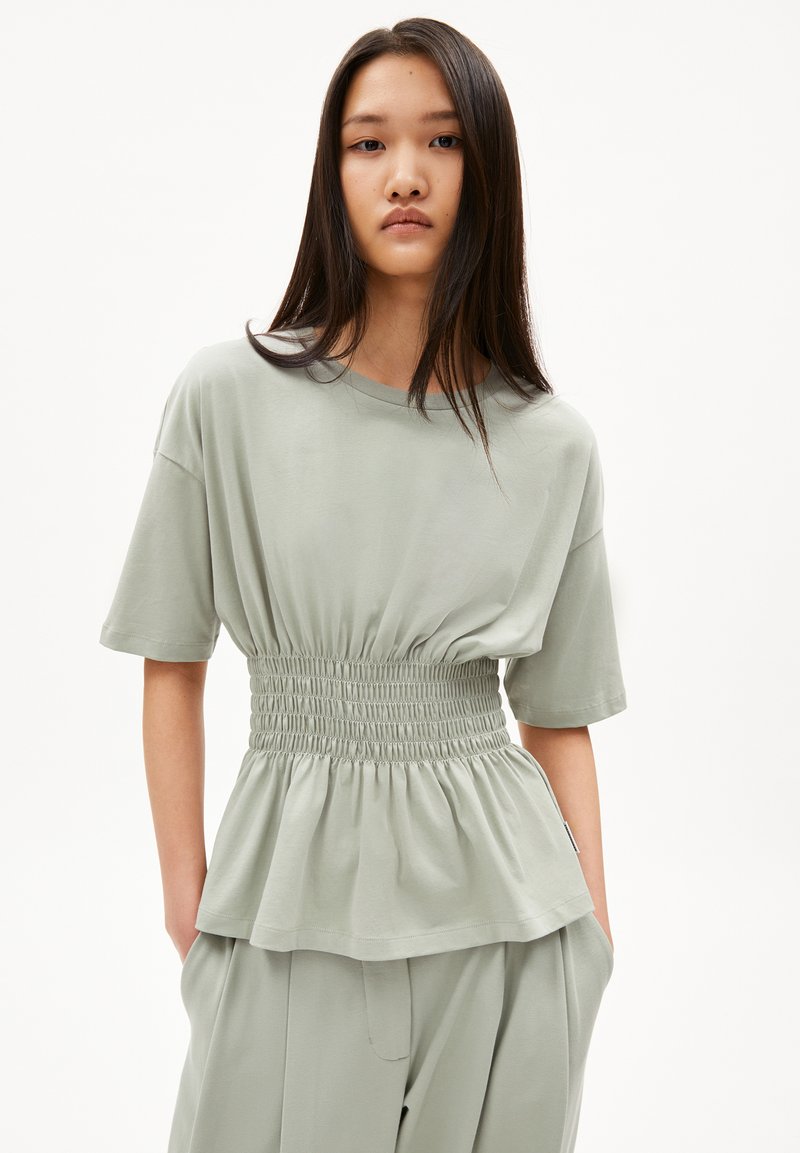 Hellgrünes Peplum-Top aus weichem Stoff, mit einem gerafften Bund und kurzen Ärmeln, lockerer Passform und rundem Ausschnitt.