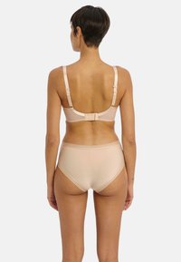 Beige bh en hooggesneden slip met verstelbare banden, zachte textuur en minimalistisch design, met een haak-en-oogsluiting aan de achterkant.