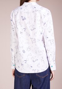 Camicia bianca con un motivo blu disegnato a mano, impreziosito da vari iconi e testo. Maniche lunghe con orlo curvato e polsini con bottone.