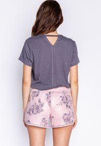 Grå kortärmad topp med V-ringning och skärning i ryggen, ihop med rosa blommönstrade shorts med en slät textur och fålldetaljer.